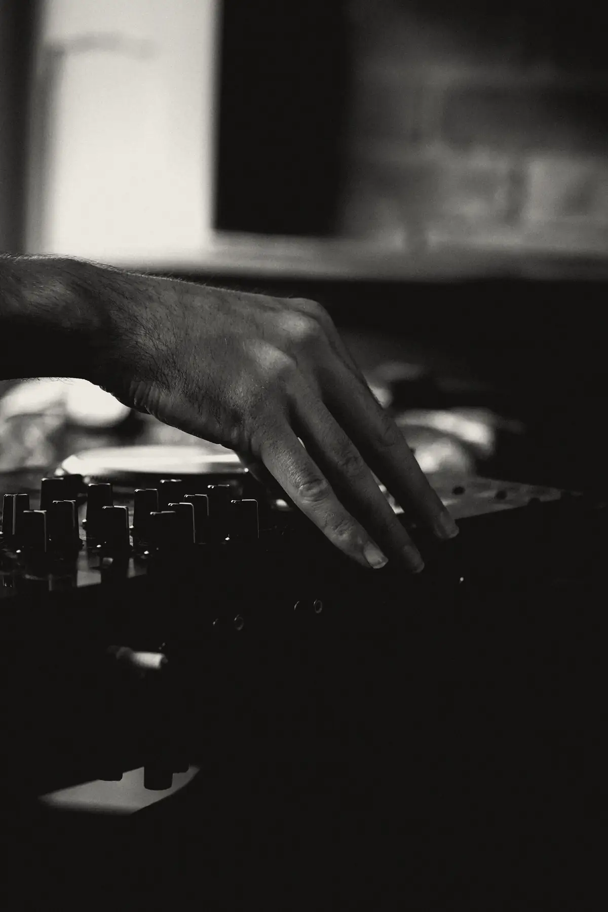 Mano sobre los controles de un mixer en penumbra